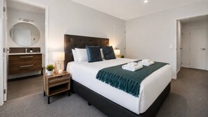 Ein modernes Hotelzimmer mit einem großen Bett, Nachttischen, einem Spiegel und einem Kleiderschrank.