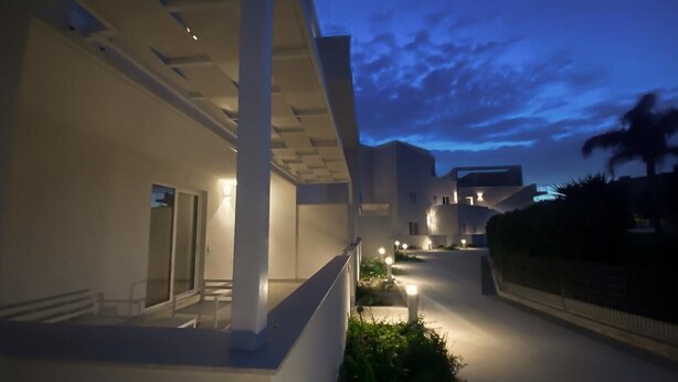 A modern building with a covered walkway, outdoor lighting, and a view of the sky at dusk. - AGATA PENTHOUSE KEYS: SEA VIEW (MODICA)