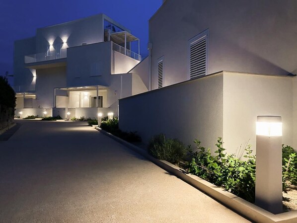Un edificio moderno con fachada plana, varios balcones y una entrada bien iluminada.