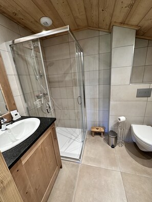 Enjoy a refreshing shower with a clear view, accompanied by a spacious vanity and mirror.
