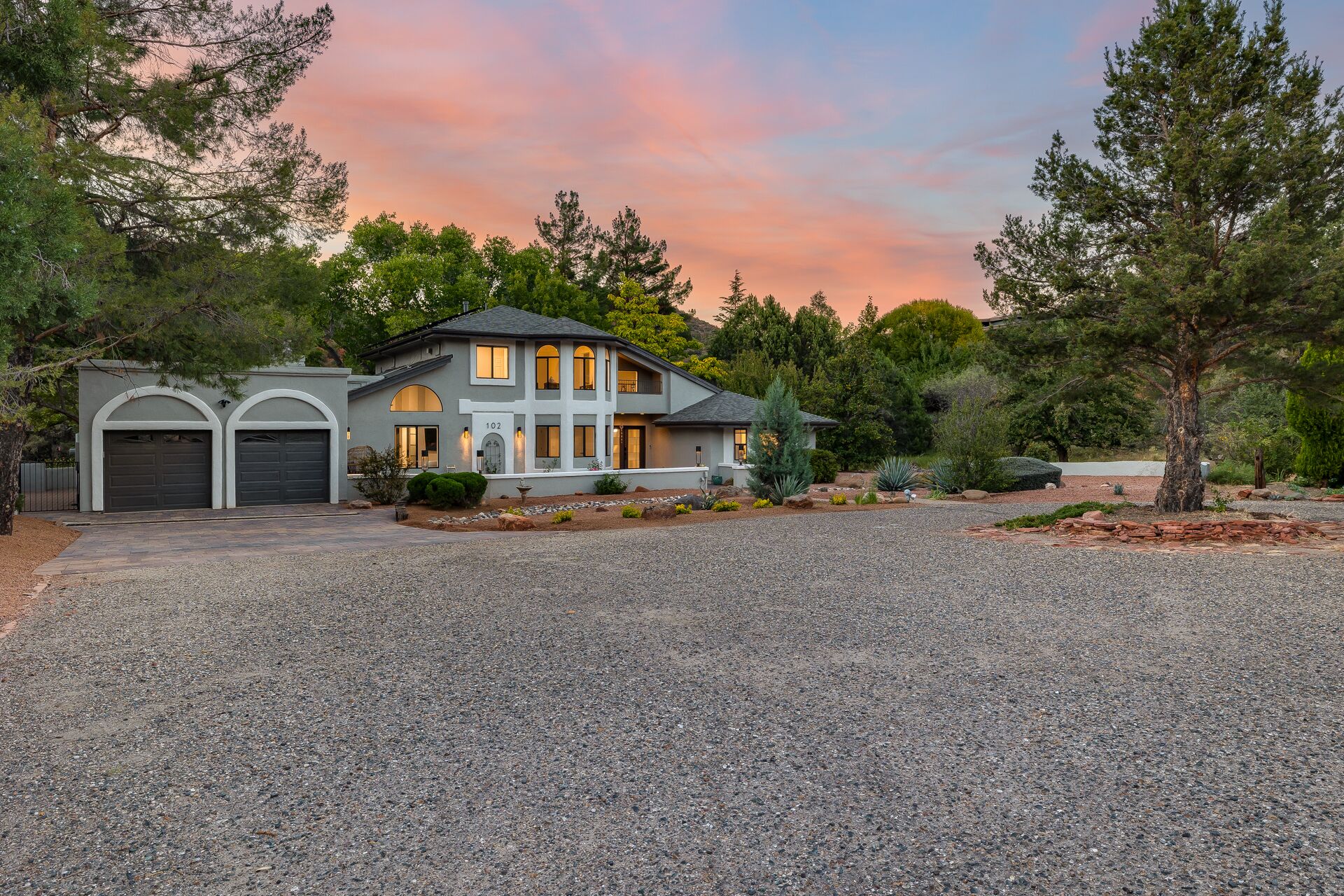Une maison à deux étages avec une allée, un garage et un jardin aménagé.