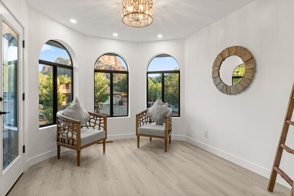A spacious room with three large arched windows offering views of a mountainous landscape. - Walk to Trails : 4BR All Kings : Hot Tub, Fire Pit (Sedona)