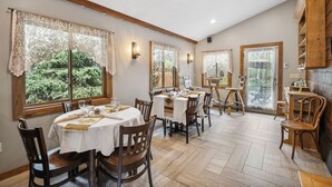 A dining area with round tables, wooden chairs, and lace curtains.