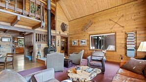 A cozy log cabin interior with a fireplace, leather furniture, and wooden walls.