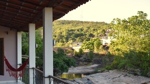 A balcony with a view of a river and a hillside.