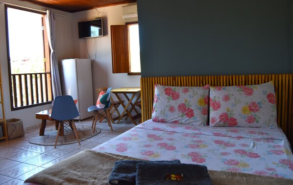 A bedroom with a bed, a desk, a chair, and a television on the wall. - Serra Grisante Pousada (Lençóis)