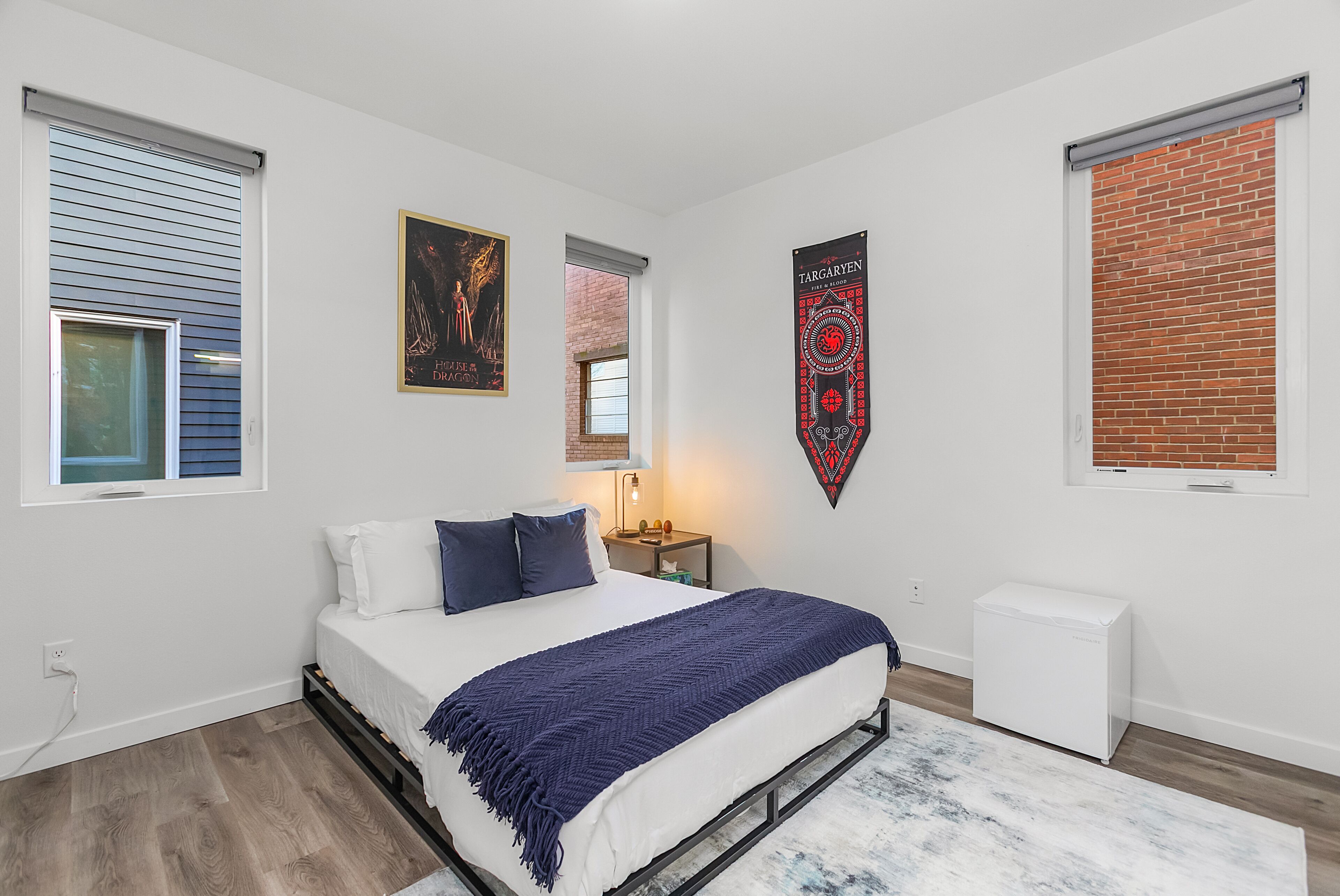 Um quarto com uma cama, uma pequena mesa de cabeceira, uma luminária, um radiador e uma janela com persianas.