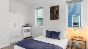 Un dormitorio con cama, escritorio, armario y ventana con persianas.
