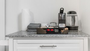 Una encimera de cocina con cafetera, hervidor, tostadora y un rollo de toallas de papel.