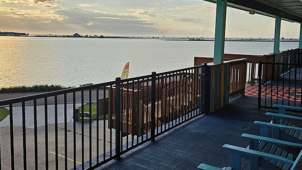 Un espace extérieur abrité, aménagé avec des sièges, d’où l’on peut admirer la vue sur l’eau et une côte lointaine.
