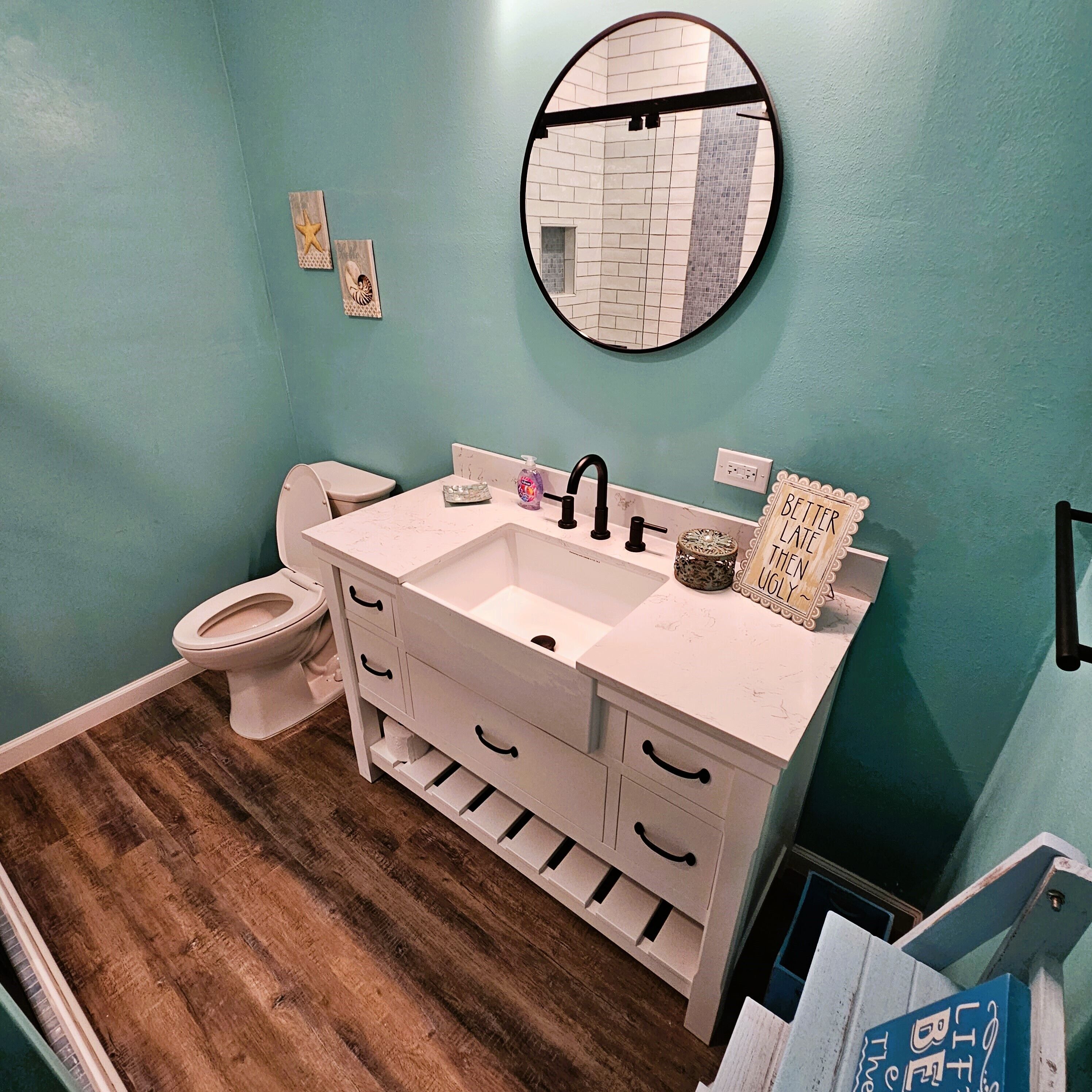 Une salle de bain avec un meuble-lavabo blanc, un miroir rond et des toilettes.