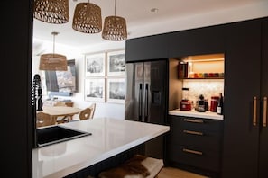A modern kitchen with a white island, dark cabinetry, and a built-in refrigerator. - White Crystal 213- ski-in ski-out (Mount Hotham)
