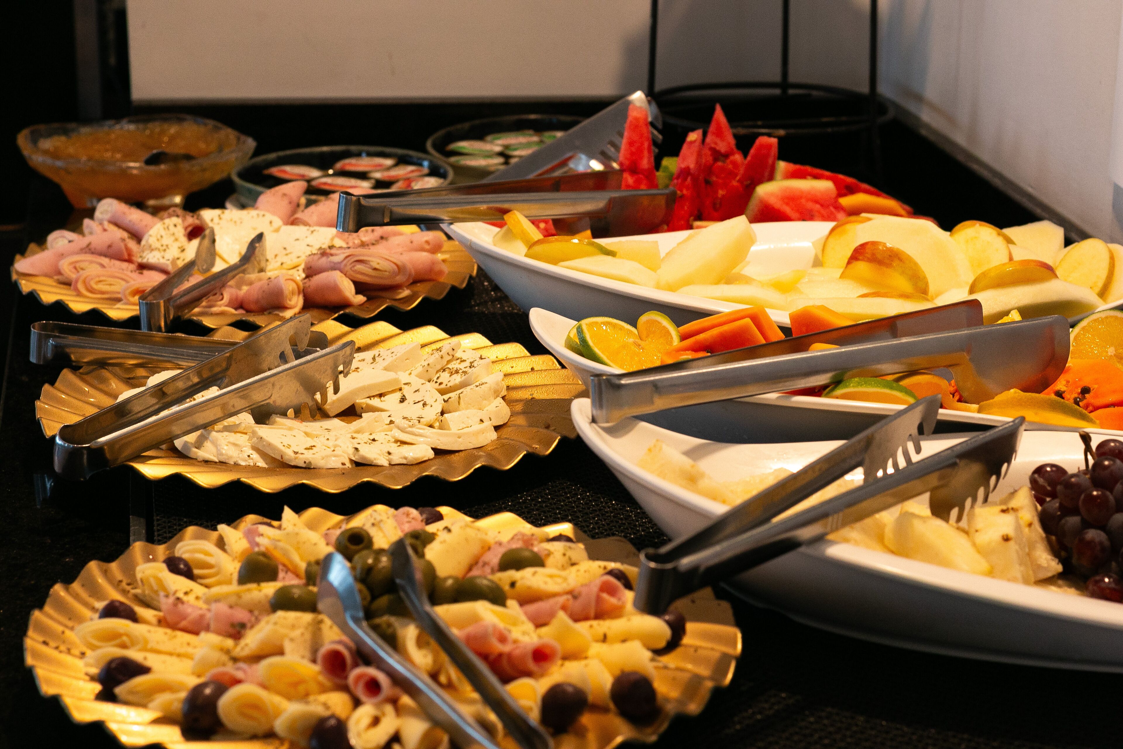 Un buffet proposant une variété d’aliments, notamment des fruits, des fromages et des viandes.