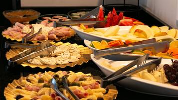 Un buffet proposant une variété d’aliments, notamment des fruits, des fromages et des viandes.