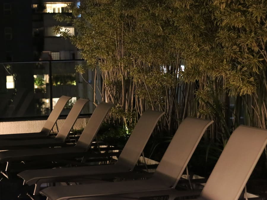 A rooftop terrace with lounge chairs and a bamboo plant wall.