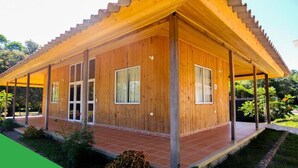 Une maison en bois dotée d’un porche abrité, de grandes fenêtres et d’une terrasse carrelée.