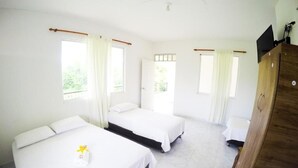 Une chambre d’hôtel avec deux lits, une armoire en bois et un téléviseur placé en hauteur.