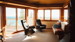 Un salon confortable, doté d’une grande fenêtre donnant sur un paysage magnifique, et aménagé avec un canapé, deux fauteuils et une table basse.