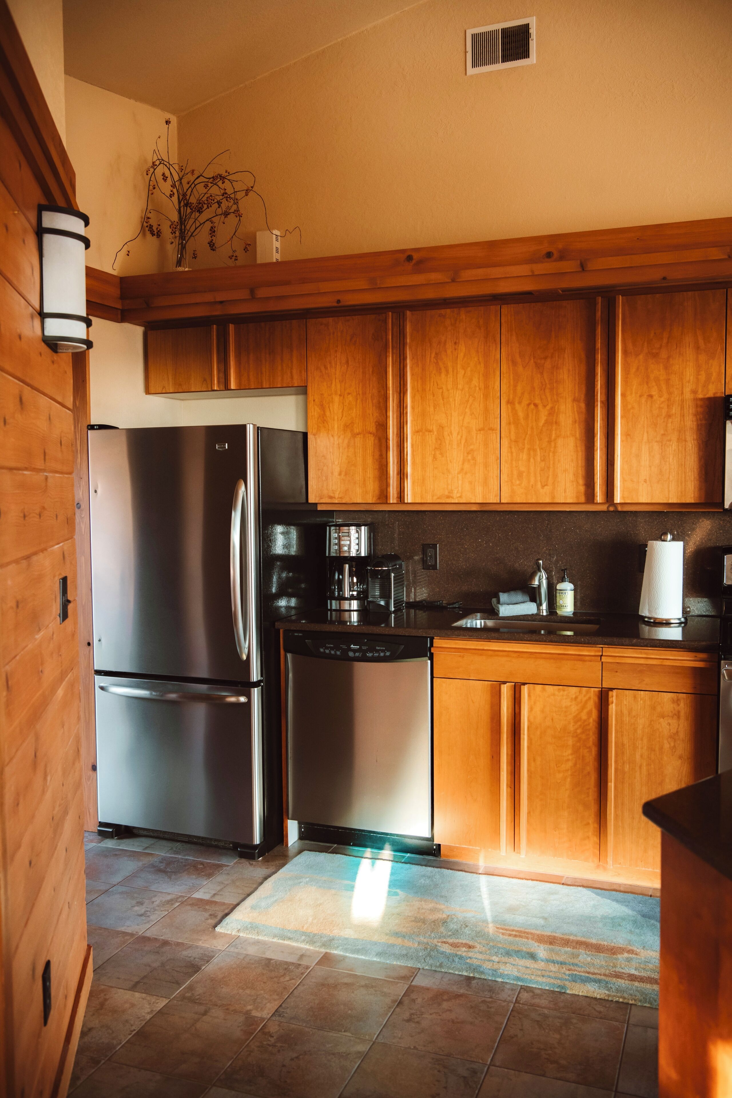 A kitchen with wooden cabinets, stainless steel appliances, and a tiled floor.