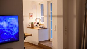 Un couloir avec un bureau, une lampe et un téléviseur.