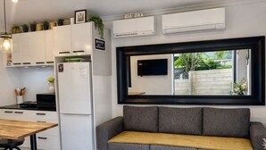 Eine moderne Küche mit weißen Schränken, einem grauen Sofa und einem an der Wand montierten Fernseher.