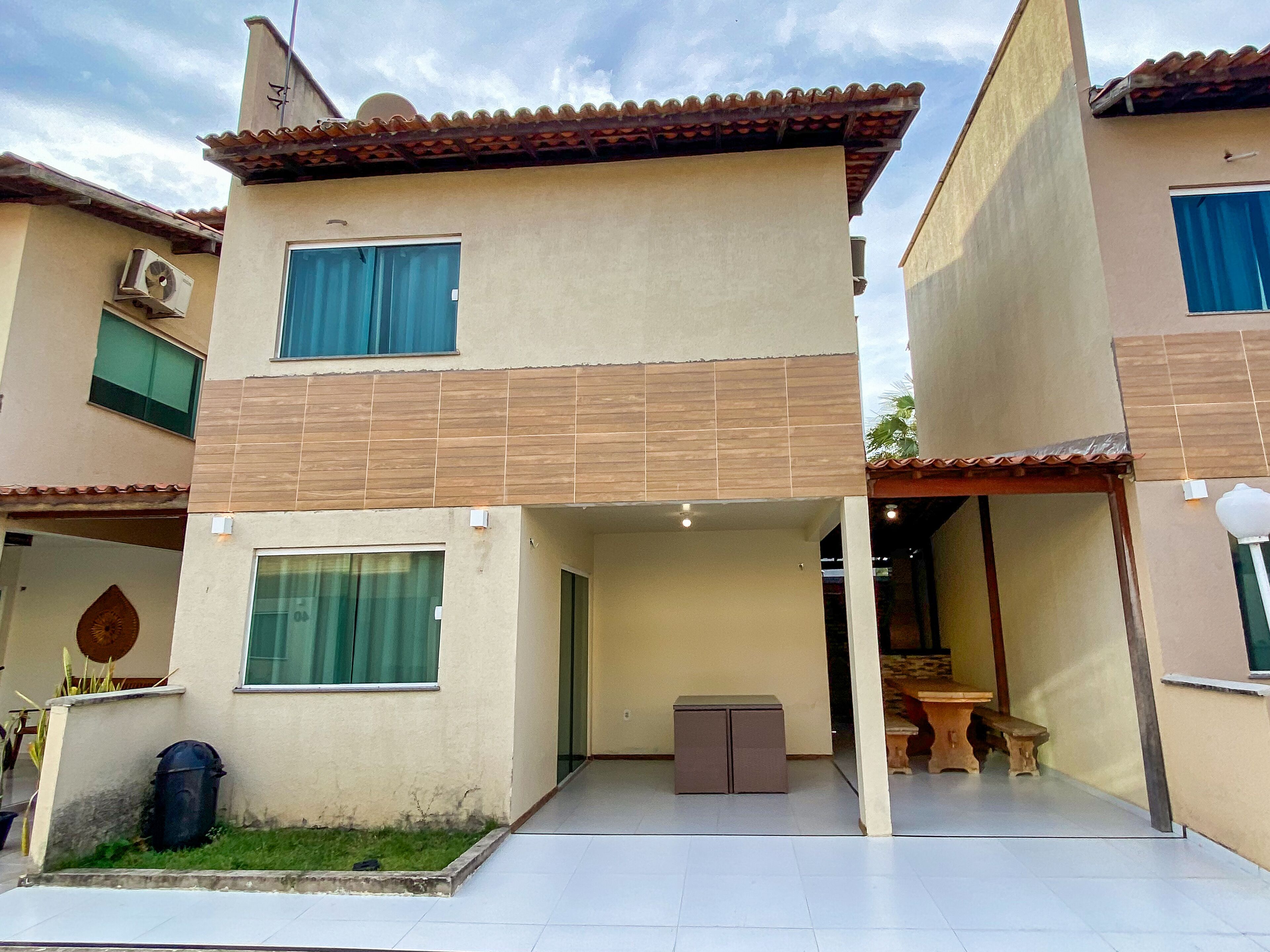 A two-story building with a flat roof, a covered patio area, and a small table and bench set.