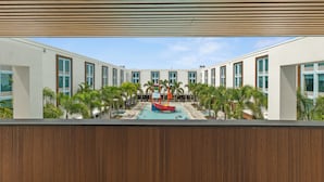 A modern hotel with a central pool area featuring a red boat and palm trees.