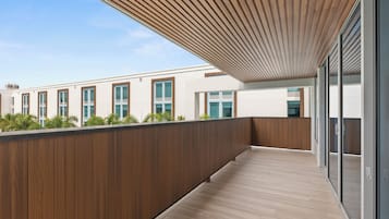 A modern building with a wooden deck, large windows, and a view of the sky.