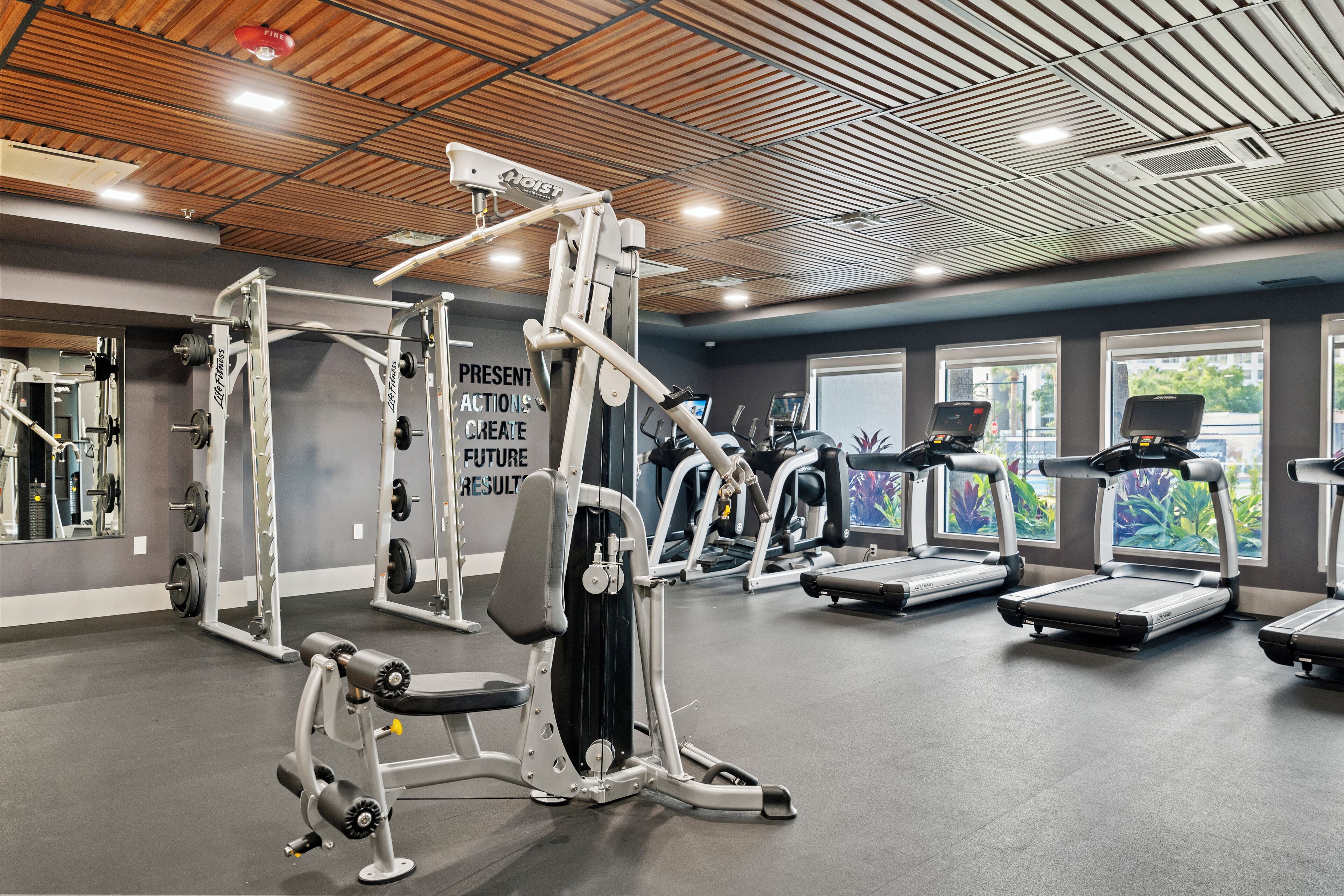 A gym with various exercise equipment, including weight machines, treadmills, and a wall with motivational text.
