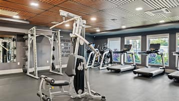 A gym with various exercise equipment, including weight machines, treadmills, and a wall with motivational text.