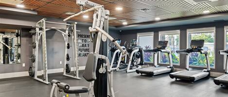 A gym with various exercise equipment, including weight machines, treadmills, and a wall with motivational text.
