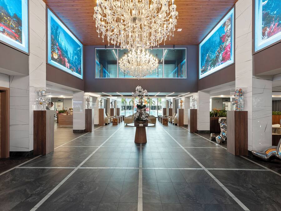 A spacious lobby with a large chandelier, seating areas, and large windows.