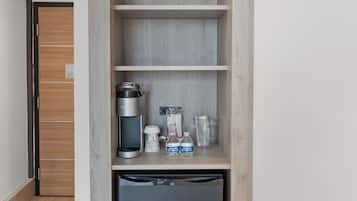 Une petite cuisine équipée comprenant un réfrigérateur intégré, une machine à café et un four à micro-ondes placé sur l’étagère supérieure.