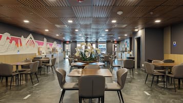 Un restaurant moderne avec des panneaux de bois au plafond, une composition florale centrale et de nombreuses tables et chaises.
