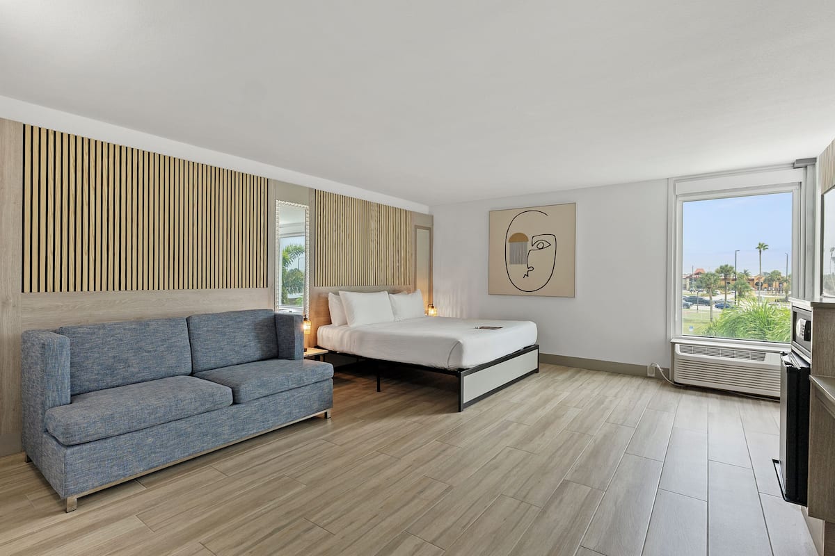 A modern bedroom with a bed, a sofa, and a large window.