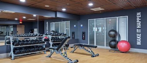 Un gimnasio con equipo de ejercicio, un espejo y mensajes motivacionales en la pared.
