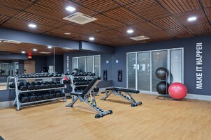 A gym with exercise equipment, a mirror, and motivational wall text.