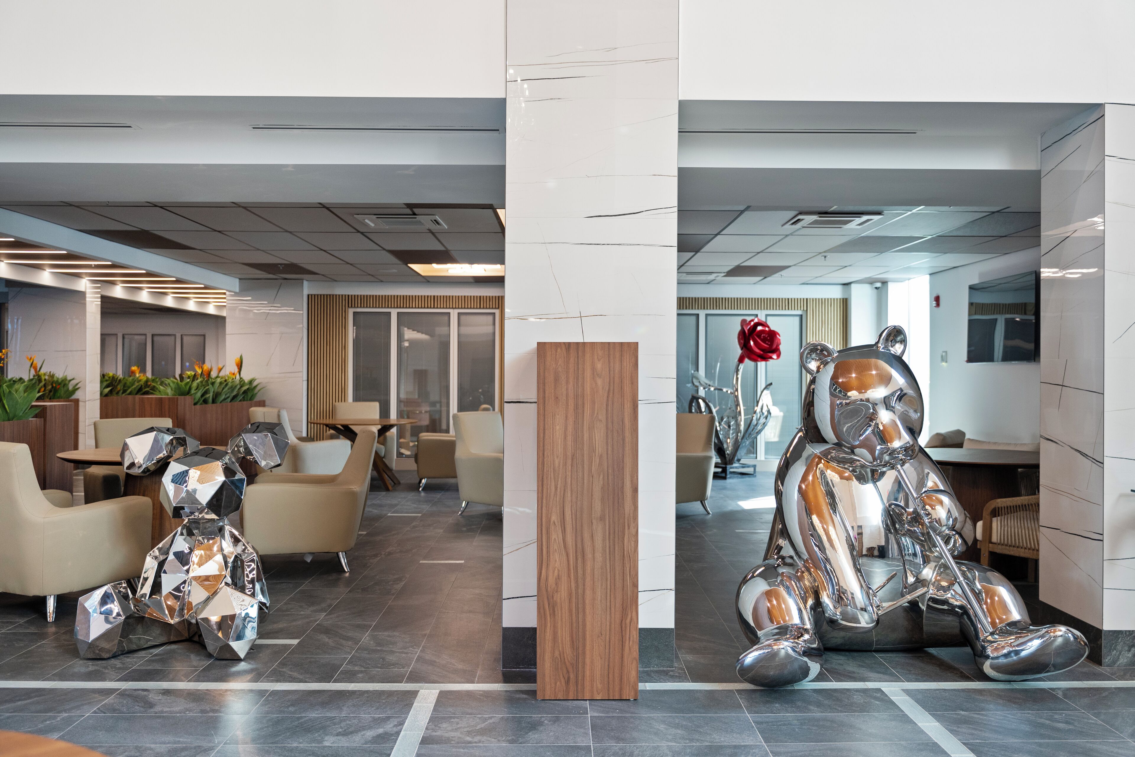 Eine moderne Lobby mit Sitzbereichen, einer Holzsäule und einer großen Metallskulptur.
