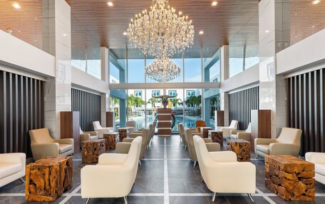 A spacious lobby with a grand chandelier, modern seating, and a view of the outdoor area.