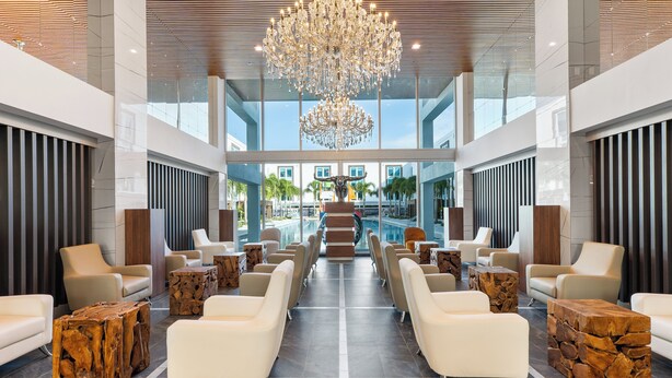 Un vestíbulo amplio con una imponente lámpara de candelabro, asientos modernos y vistas al área exterior.