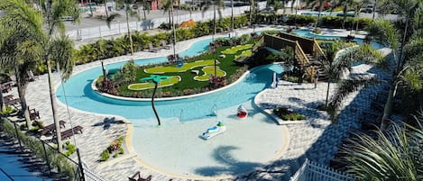 A pool area with a winding pool design, lounge chairs, and a small shark-shaped float.
