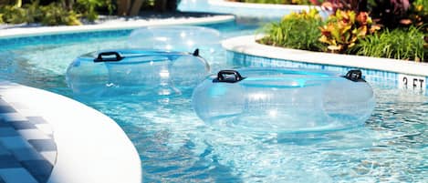 A swimming pool with inflatable rings, a wooden deck, and a covered area with plants.