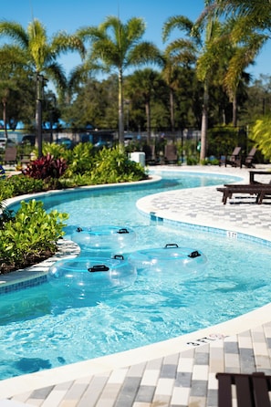 A swimming pool with three inflatable rings, surrounded by palm trees and lounge chairs. - Kompose Boutique Resort at Theme Parks (Kissimmee)