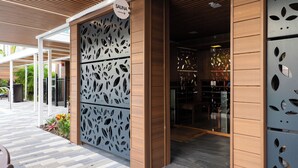 Entrada de un spa con fachada de madera, un letrero que indica una sauna y una partición de metal con diseño.