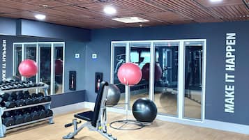 A gym with exercise equipment, mirrors, and motivational wall text.