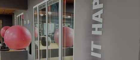 A gym interior with exercise balls, a motivational wall sign, and wooden flooring.
