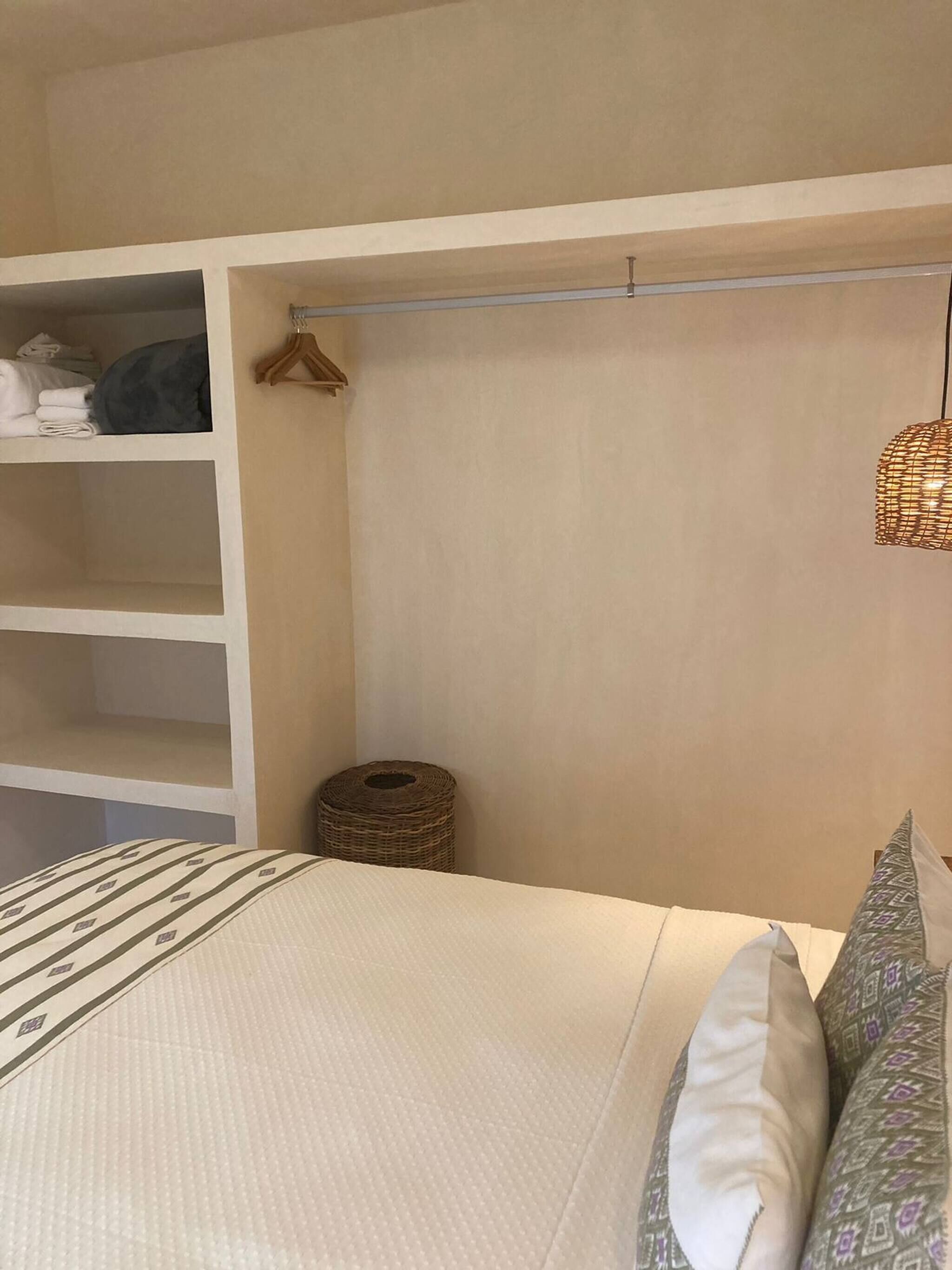 A bedroom with a bed, a wardrobe, and a hanging light fixture.