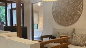 Ein modernes Interieur mit einer Holztreppe, einer runden Wanddekoration und einem Essbereich, der durch einen Durchgang sichtbar ist.