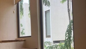 Eine Treppe mit Holzhäuschen führt zu einem Fenster mit Blick auf ein Gebäude und Grünflächen.