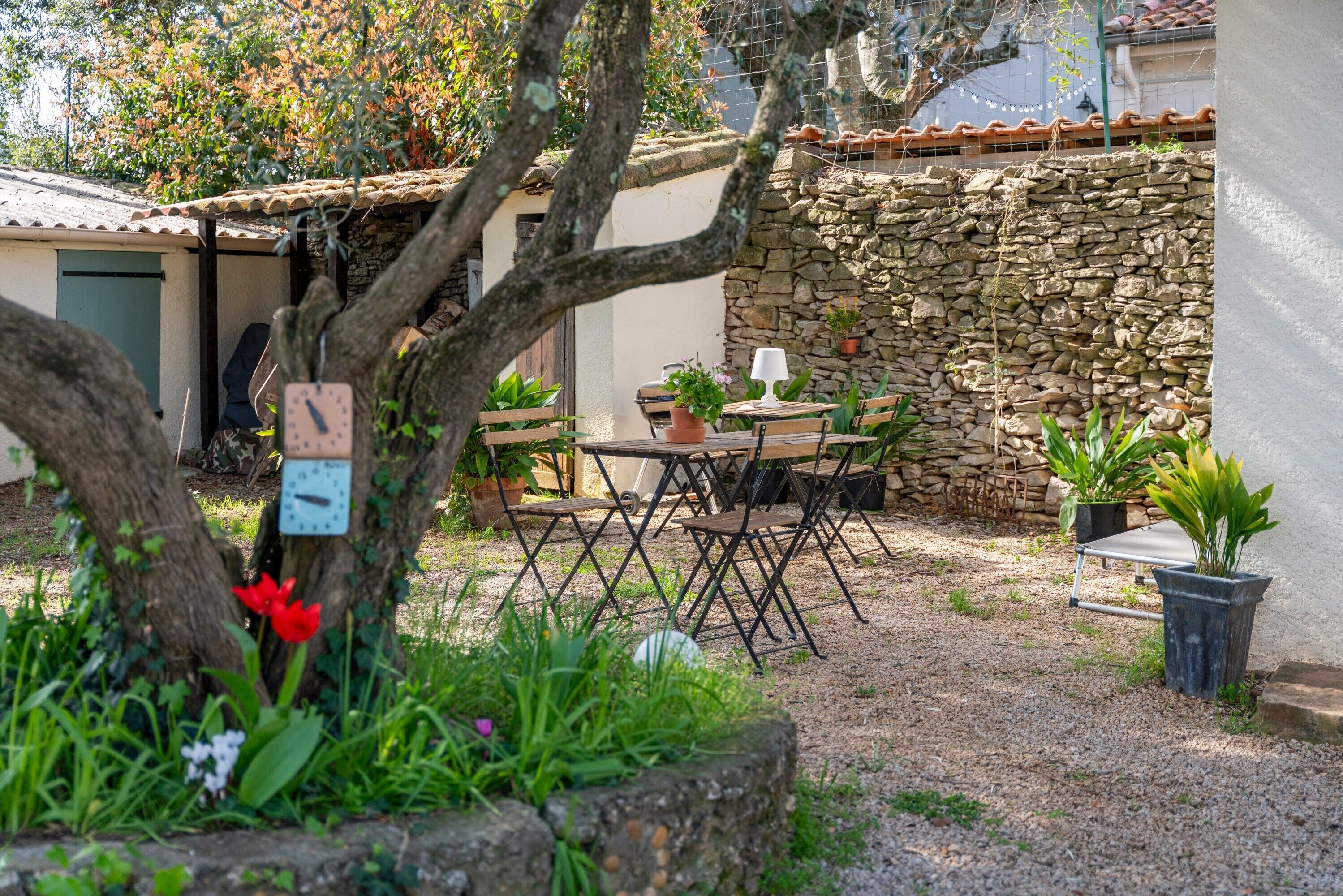Un espace extérieur aménagé dans un style rustique, avec un mur en pierre, une table en bois et des chaises.